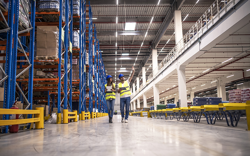 Distribution warehouse interior with workers wearing hardhats an